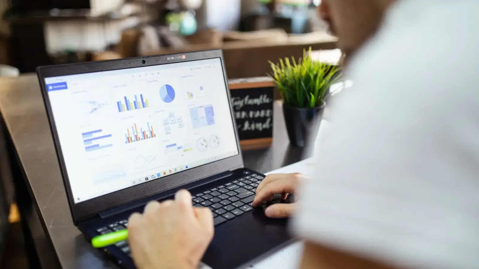 A laptop showing charts and graphs while someone types