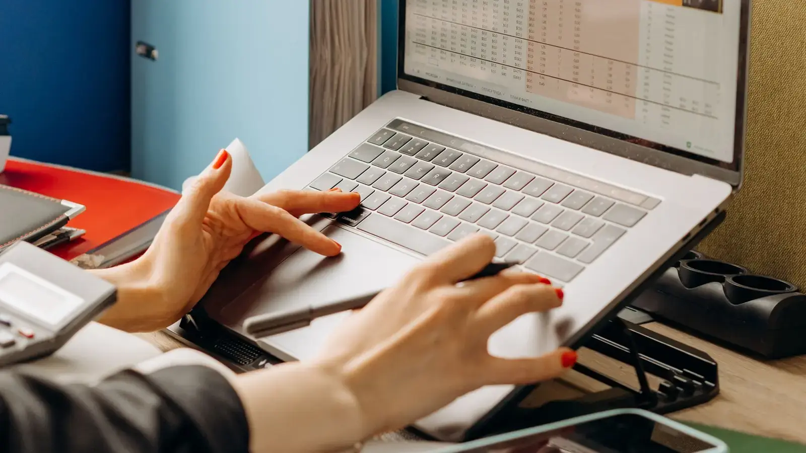 A laptop showing a spreadsheet beside office binders